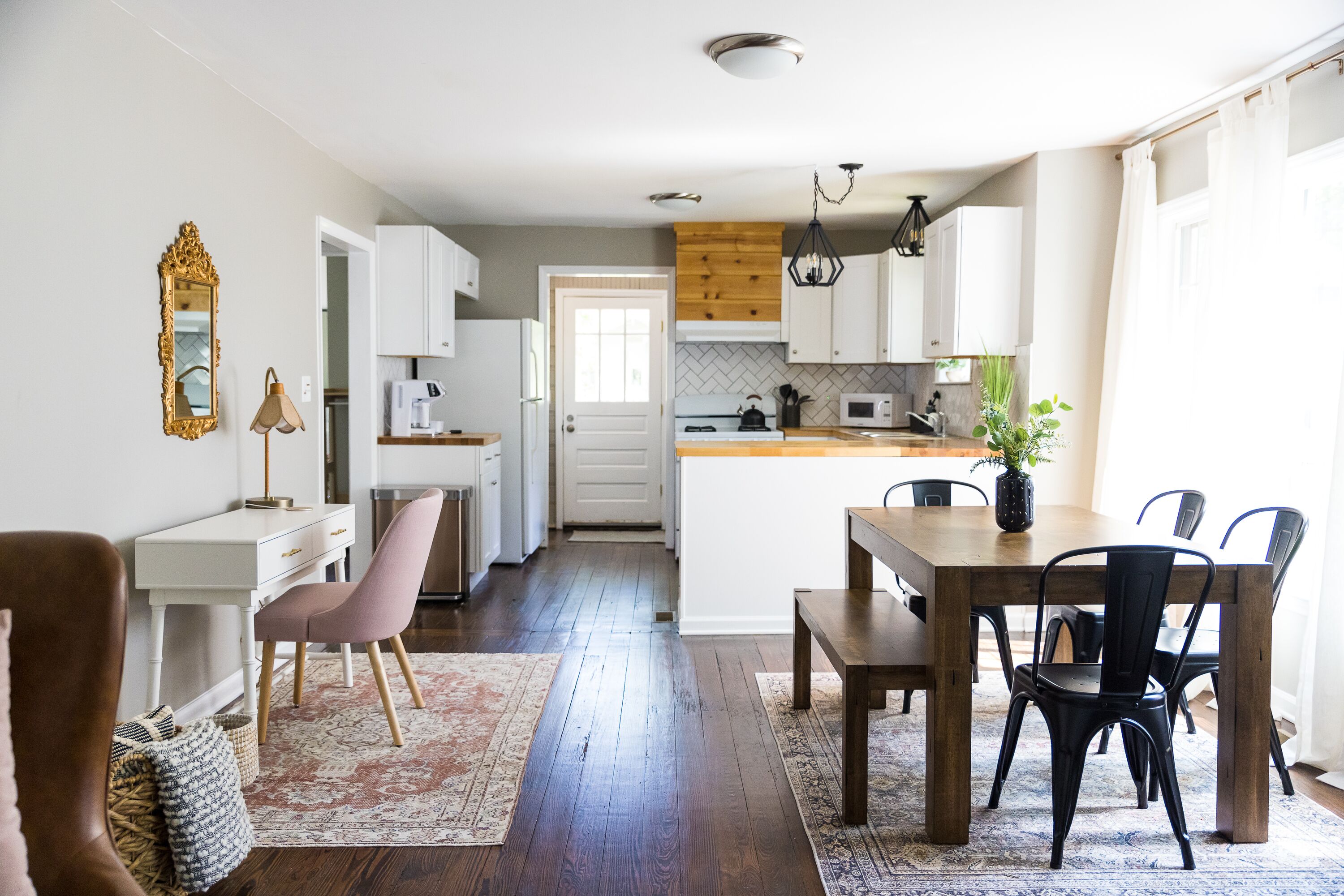 Une cuisine moderne avec des meubles blancs, un îlot central en bois et un coin repas comprenant une table et des chaises.