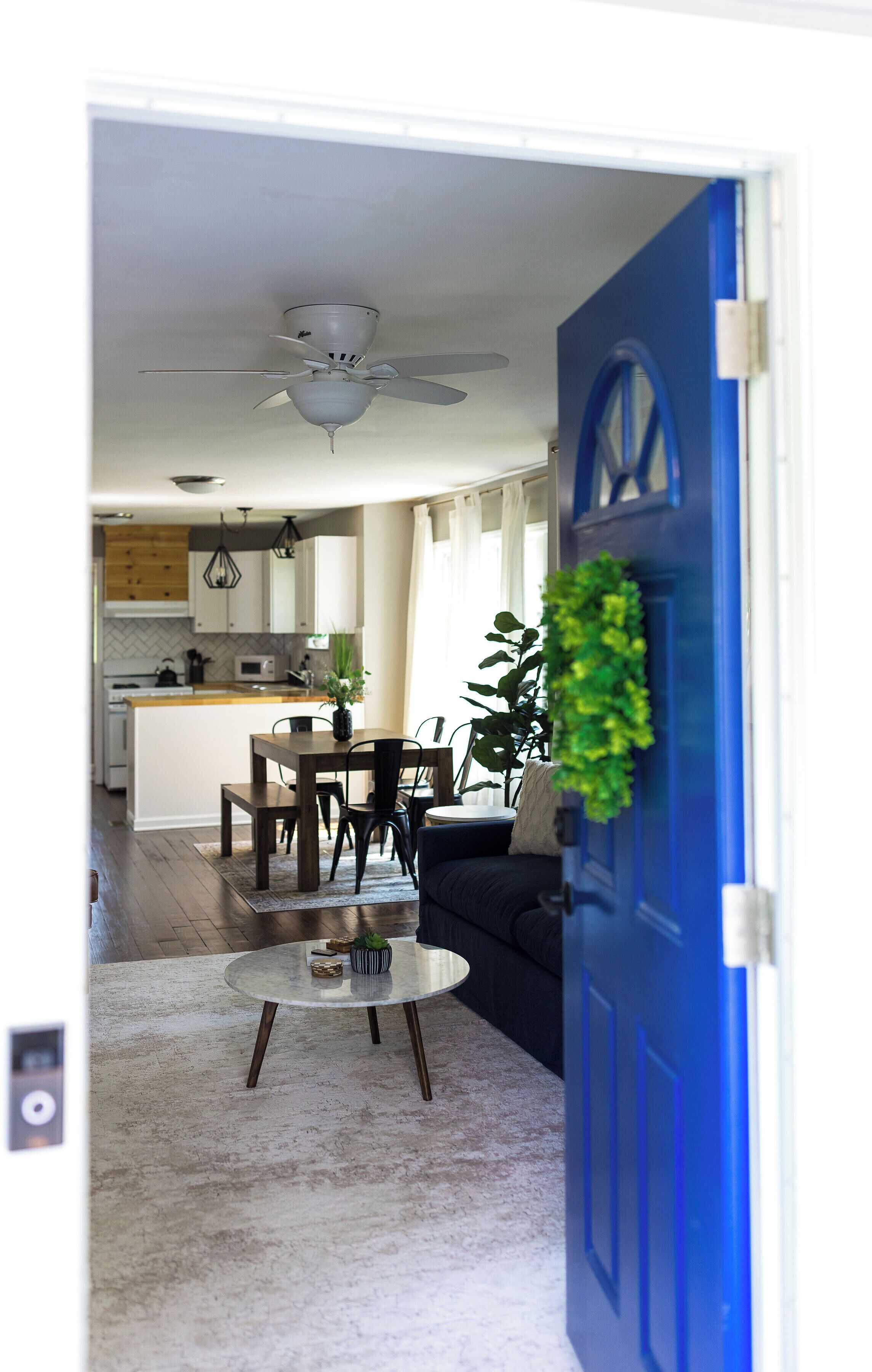 A modern kitchen with white cabinets, a wooden countertop, and a ceiling fan.