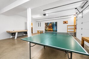 Ein Pingpongtisch in einem Raum mit weißen Wänden, einer Holzbank und einem Bärenbild.
