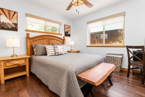 A bedroom with a bed, bedside tables, a bench, a chair, and a ceiling fan.