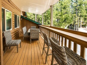 A wooden deck with wicker furniture and a view of trees.