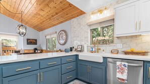 Een moderne keuken met blauwe kastjes, een houten plafond en een roestvrijstalen vaatwasser.