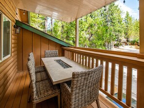 Eine Holzterrasse mit Tisch und Stühlen, mit Blick auf eine grüne Landschaft mit Bäumen.