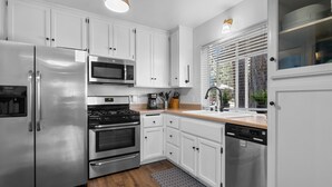 Una cucina moderna con elettrodomestici in acciaio inossidabile, mobili bianchi e pavimento in legno.