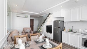 A modern kitchen with white cabinetry, a stainless steel refrigerator, and a built-in oven. - Luxury loft penthouse @ Ben Thanh Tower (hồ chí minh)