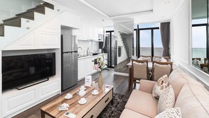 A modern living room with a flat-screen TV, a wooden coffee table, and a beige sofa. - Luxury loft penthouse @ Ben Thanh Tower (hồ chí minh)