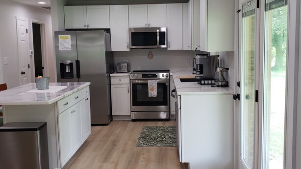 A modern kitchen with white cabinets, stainless steel appliances, and a central island. - All Newly remodeled-- stylish luxury nestled in rural neighborhood - Forest View (Stanton)