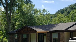 A two-story brick building with a front porch, a driveway, and a parked vehicle. - All Newly remodeled-- stylish luxury nestled in rural neighborhood - Forest View (Stanton)