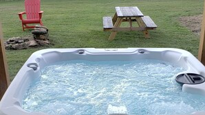 A hot tub in a backyard with a wooden fence, a picnic table, and a red chair. - All Newly remodeled-- stylish luxury nestled in rural neighborhood - Forest View (Stanton)