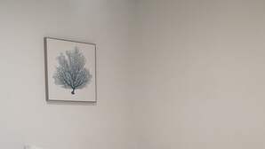 A bedroom with a large bed, white bedding, a teal throw blanket, a nightstand with a phone, and a framed picture of a tree on the wall. - All Newly remodeled-- stylish luxury nestled in rural neighborhood - Forest View (Stanton)