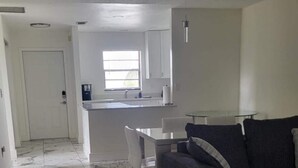 Una zona saló àmplia amb terra de marbre, un sof à gris i una taula de dinar amb cadires.