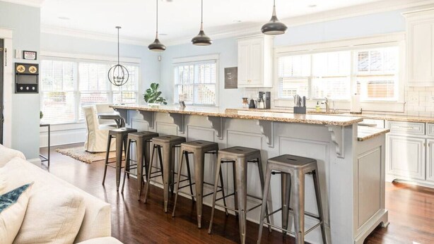 A modern kitchen with a central island, bar stools, pendant lighting, and large windows. - Luxury 6-Bedroom Home in Prime Decatur Neighborhood, Near DT ATL (Decatur)