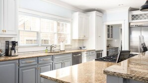 A modern kitchen with white cabinetry, granite countertops, a stainless steel refrigerator, and a built-in oven. - Luxury 6-Bedroom Home in Prime Decatur Neighborhood, Near DT ATL (Decatur)