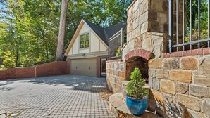 A house with a stone exterior, a brick driveway, and a small garden with a potted plant. - Luxury 6-Bedroom Home in Prime Decatur Neighborhood, Near DT ATL (Decatur)
