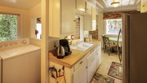 A compact kitchen with a washing machine, a coffee maker, and a sink.