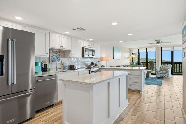 A modern kitchen with white cabinetry, stainless steel appliances, and a large island.