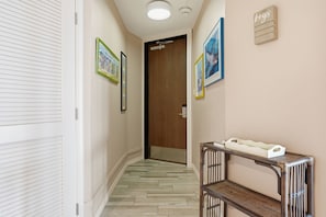 Un pasillo con puerta de madera, obra de arte enmarcada, una consola con bandeja y un panel de pared para llaves.