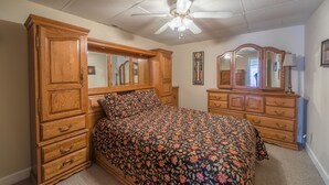 Ein Schlafzimmer mit einem großen Bett, einem Holzschrank und einem Deckenventilator.
