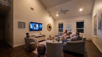 Een moderne woonkamer met een flatscreen televisie, comfortabele zithoek en een plafondventilator.