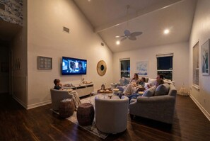 A modern living room with a flat-screen TV, comfortable seating, and a ceiling fan.