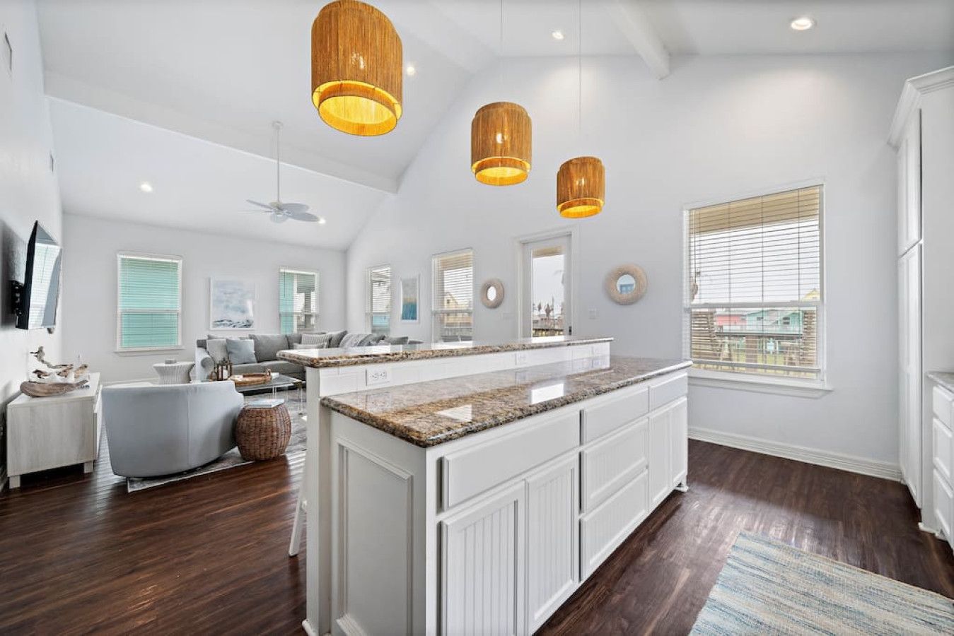 A spacious kitchen with a central island, white cabinetry, and pendant lighting.