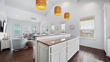 A spacious kitchen with a central island, white cabinetry, and pendant lighting.