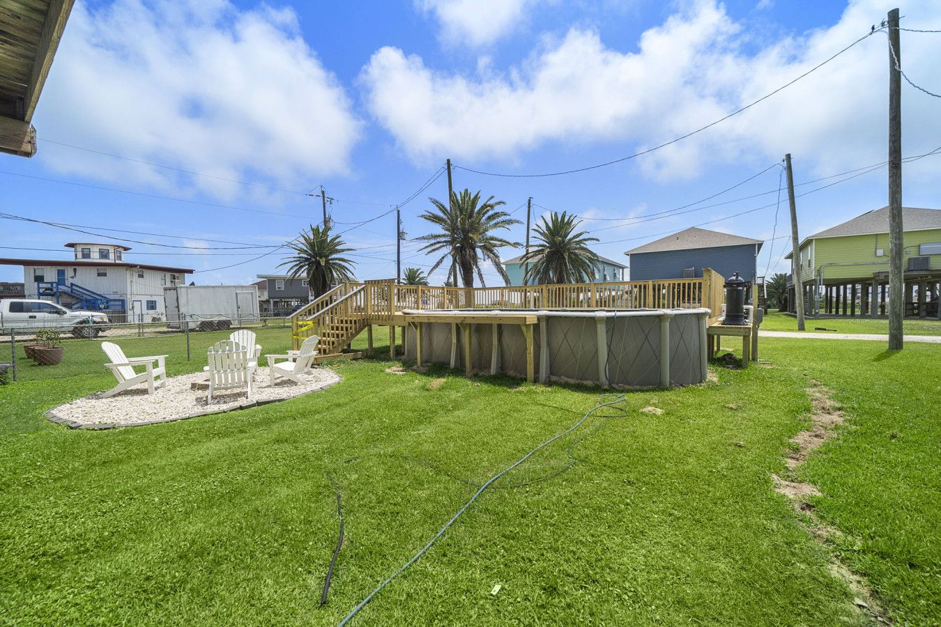 A backyard with a wooden deck, outdoor seating, and a swimming pool.