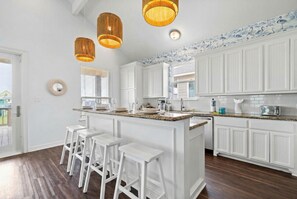 A kitchen with white cabinets, a central island with bar stools, and pendant lights.