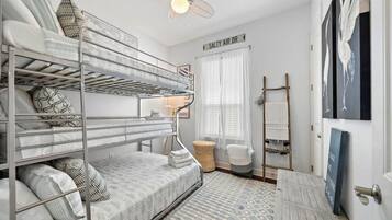 A bunk bed room with a ceiling fan, a sign reading "SALTY AIR DR", and a ladder for hanging clothes.
