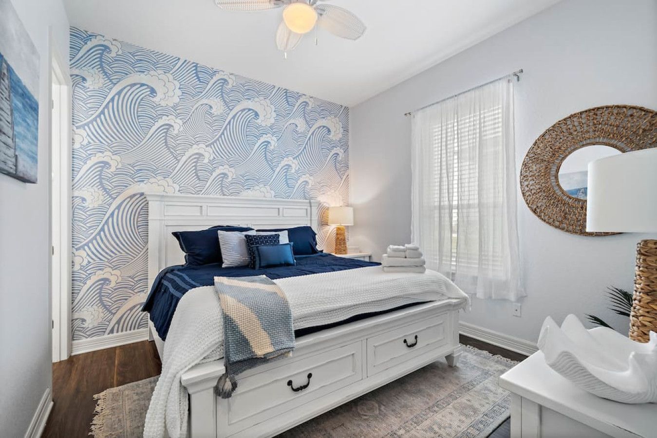 A bedroom with a bed, bedside table, lamp, and a wall with a wave pattern.