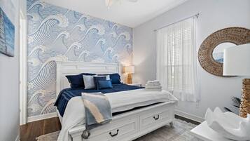 A bedroom with a bed, bedside table, lamp, and a wall with a wave pattern.