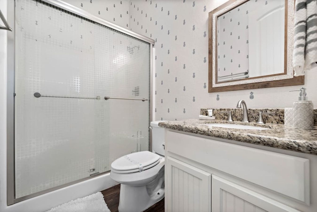 A bathroom with a shower, toilet, sink, and mirror.