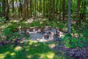 Surrounded by a forest, this outdoor space features a circular seating area with wooden stumps.