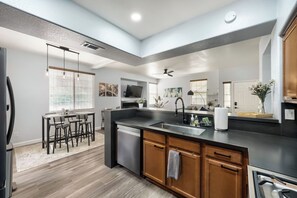 A modern kitchen with a central island, built-in appliances, and a dining area with a bar stool. - RARE GATED NEWLY REMODELED Summerlin Luxury 2 Bed / 2 Bath Condo (Las Vegas)
