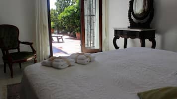 A hotel room with a bed, a chair, a table, and a window with a view of the outside.