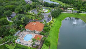 Vista aérea de un complejo turístico con piscina, campo de golf y lago.