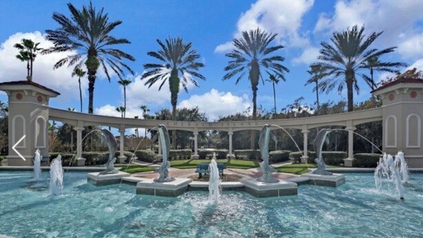 Una piscina con varias fuentes y palmeras al fondo.