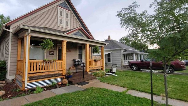 Ein eingeschossiges Haus mit einer Veranda, einem kleinen Vorgarten und einer Auffahrt.