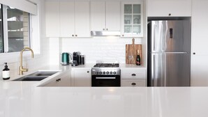 Una cocina moderna con armarios blancos, un refrigerador de acero inoxidable, una estufa a gas y un horno empotrado.