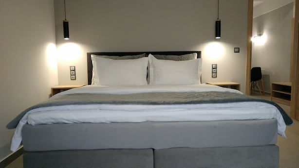 A modern bedroom with a large bed, two bedside tables, and pendant lights.