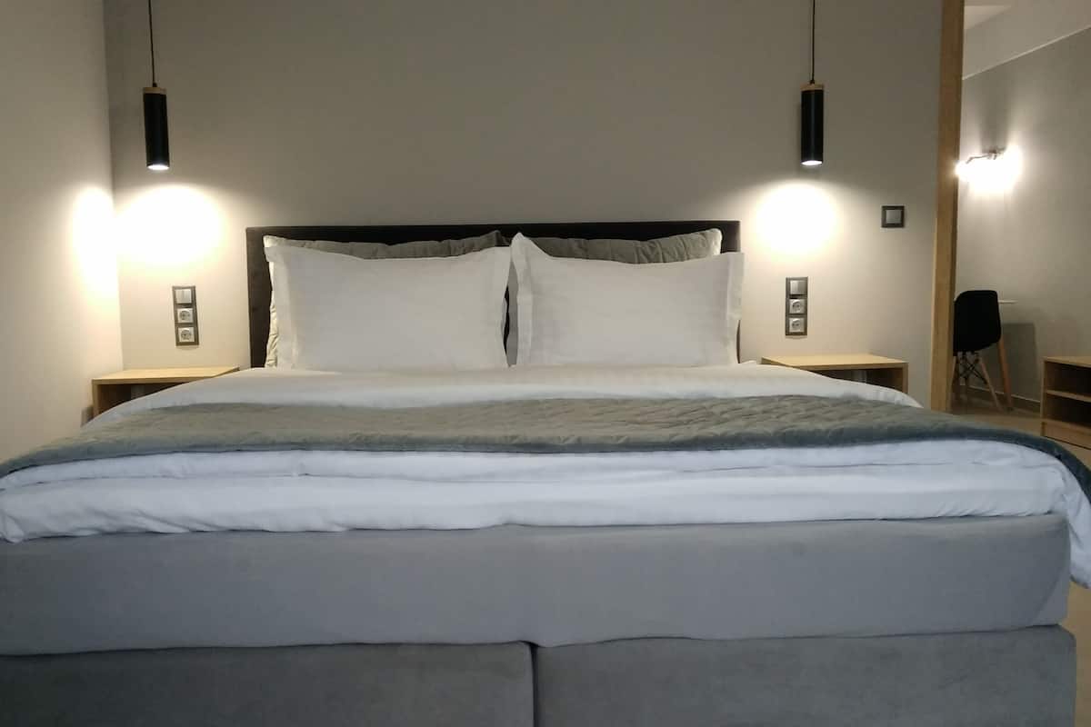 Un dormitorio moderno con una cama grande, dos mesitas de noche e iluminación colgante.
