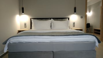 Quarto moderno com uma cama grande, duas mesas de cabeceira e luminárias pendentes.