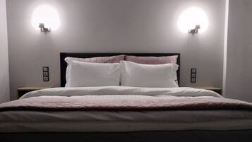 Ein ordentlich bezogenes Bett mit Kopfteil, zwei Nachttischen und Wandleuchten.