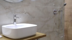 A bathroom with a white sink, a mirror, and a shower.