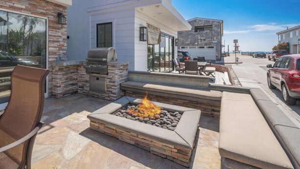 Eine Terrasse im Freien mit einem Steinkamin, Sitzgelegenheiten und einem Grill.