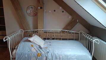 A loft-style bedroom with a metal bed frame, a wooden ceiling beam, and a skylight.