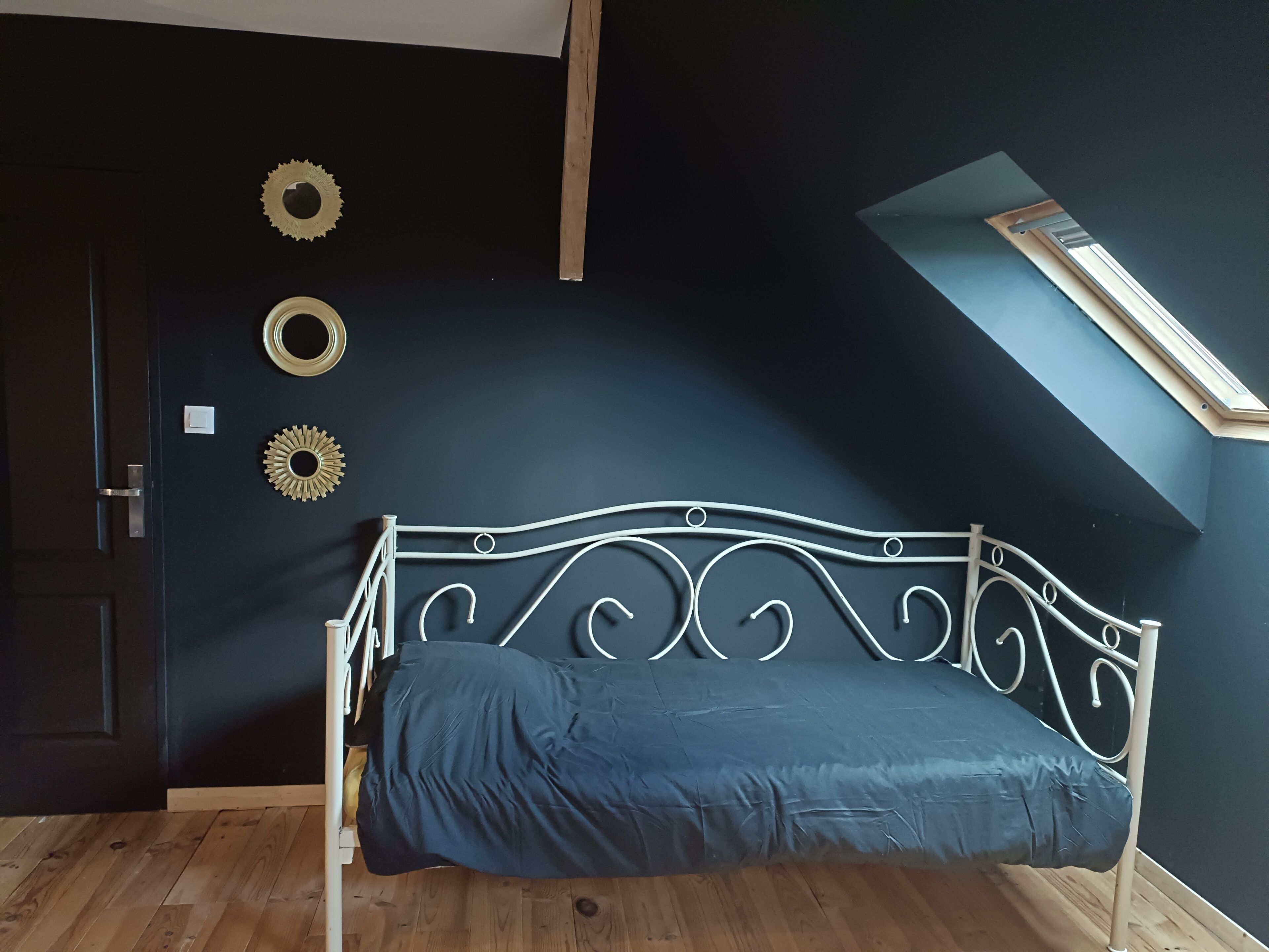 Een kamer met een bed, dakraam en decoratieve muurkunst.
