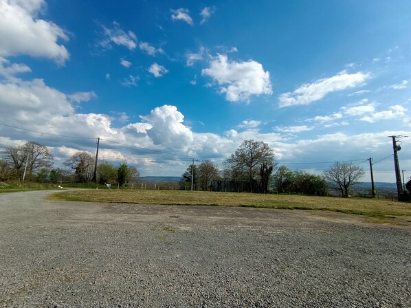 Un camino de grava con cielo despejado y árboles a lo lejos.