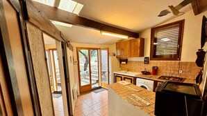 Une cuisine avec des meubles de rangement en bois, une cuisinière à gaz et une fenêtre équipée de stores.