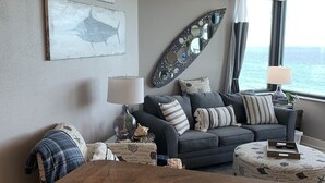 Un salón acogedor con un sofá gris, una mesa de centro redonda y un espejo decorativo grande.